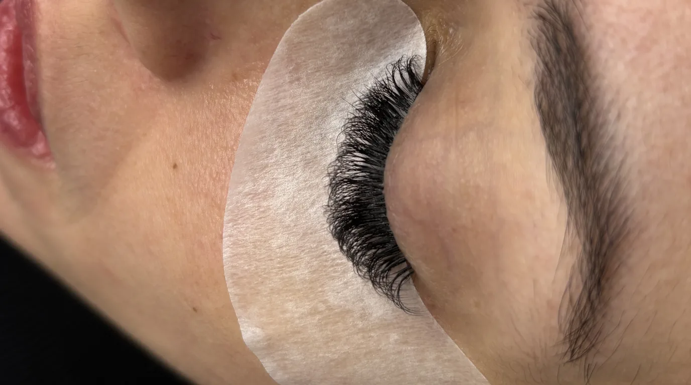 Perfil do olho de uma cliente com a extensão de cílios aplicada e o pad de silicone sob o olho, no Studio Crystal Lashes